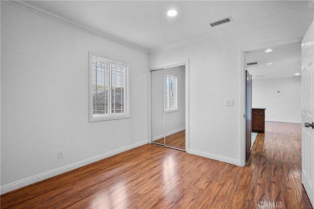 unfurnished bedroom with ornamental molding, hardwood / wood-style floors, and a closet