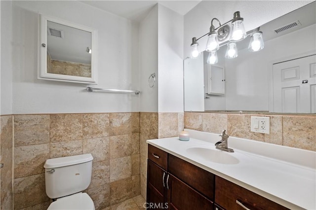 bathroom featuring tile walls, vanity, and toilet