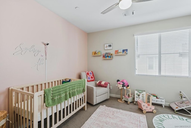 bedroom with a nursery area, ceiling fan, and carpet flooring