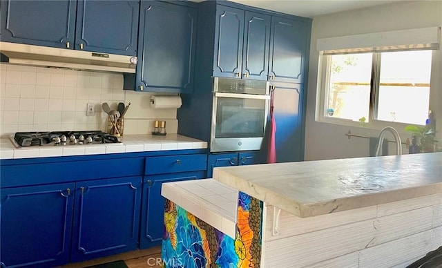 kitchen with tile counters, blue cabinetry, and appliances with stainless steel finishes