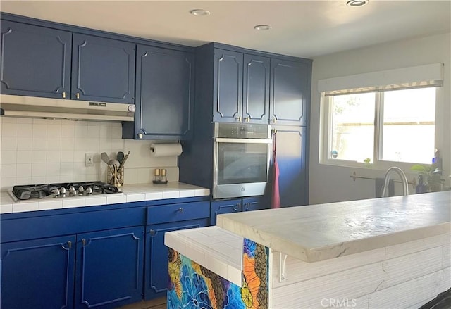 kitchen with backsplash, tile counters, stainless steel appliances, and blue cabinets