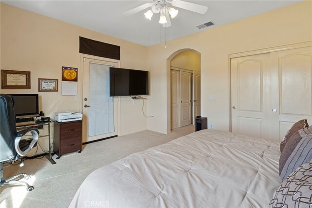 bedroom with two closets, light carpet, and ceiling fan