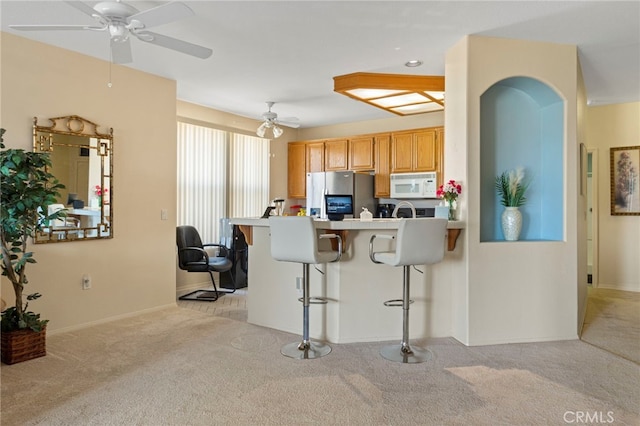 kitchen with a breakfast bar area, light colored carpet, ceiling fan, kitchen peninsula, and stainless steel refrigerator with ice dispenser