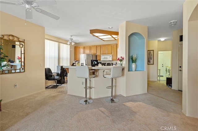 kitchen featuring a kitchen bar, light brown cabinetry, stainless steel fridge with ice dispenser, light colored carpet, and kitchen peninsula