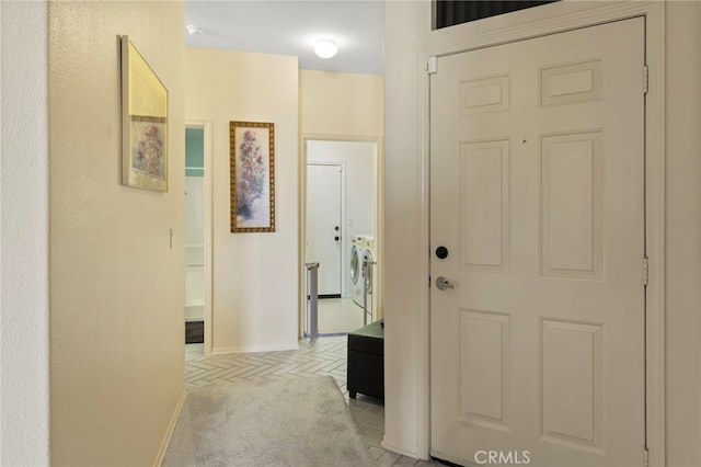 hall featuring light colored carpet and washer and dryer