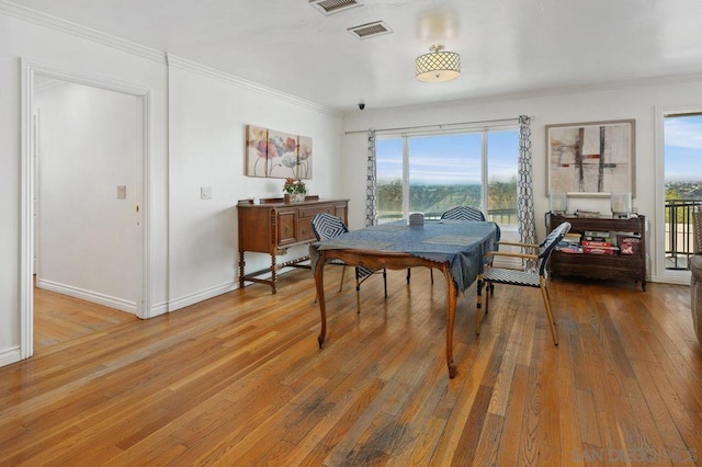 dining area with hardwood / wood-style floors, a wealth of natural light, and ornamental molding