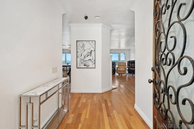 hallway with ornamental molding and light hardwood / wood-style flooring