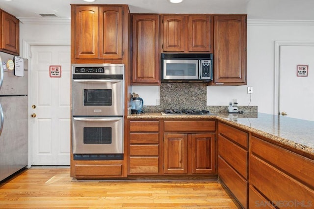 kitchen featuring light stone countertops, appliances with stainless steel finishes, crown molding, and light hardwood / wood-style floors