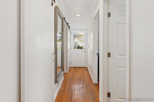 hall featuring crown molding, a barn door, and light hardwood / wood-style floors