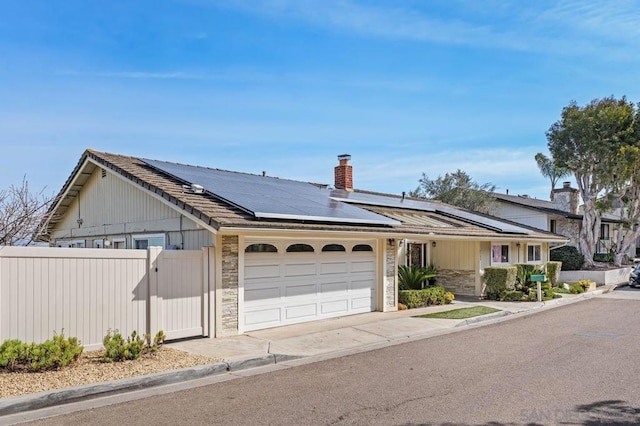 ranch-style home featuring a garage and solar panels