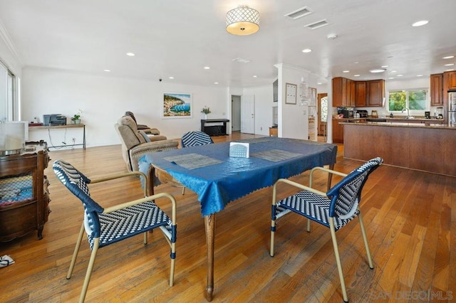 dining space with ornamental molding, sink, and light wood-type flooring