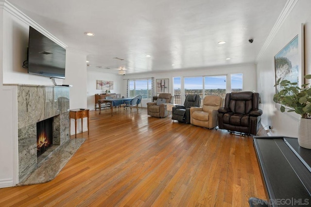 living room featuring ornamental molding, a high end fireplace, and light hardwood / wood-style floors