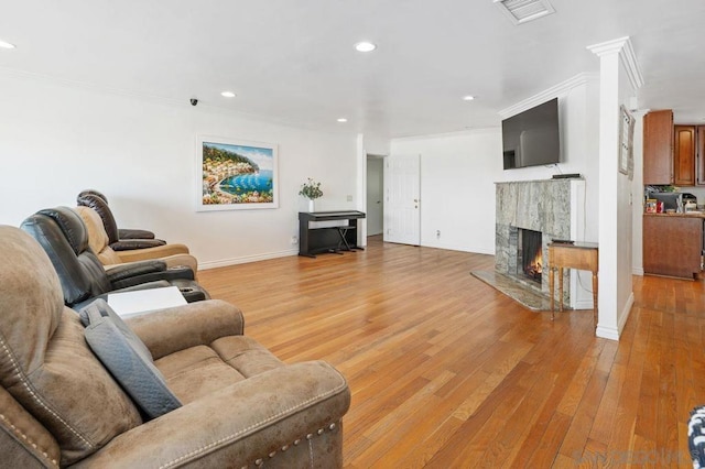 living room featuring light hardwood / wood-style flooring, a high end fireplace, and ornamental molding