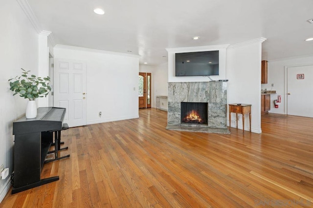 living room with ornamental molding, a premium fireplace, and light wood-type flooring