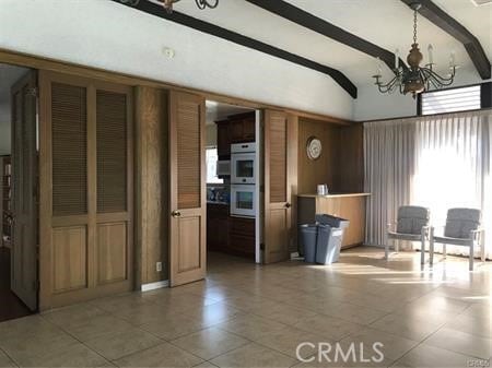 interior space featuring beamed ceiling, tile patterned flooring, and an inviting chandelier