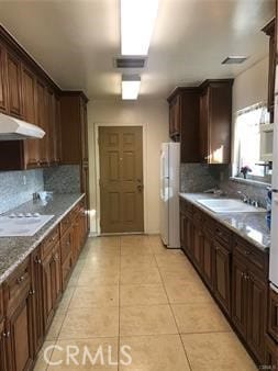 kitchen featuring white appliances, sink, decorative backsplash, and light tile patterned floors