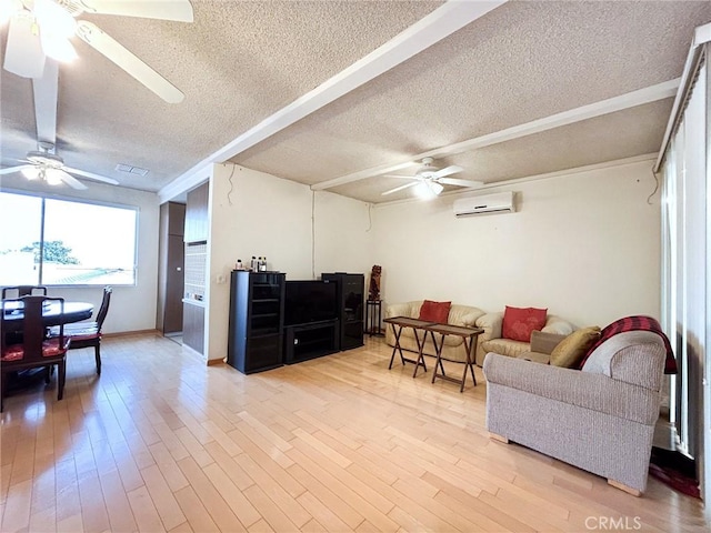 living room featuring ceiling fan, an AC wall unit, a textured ceiling, and light wood-type flooring