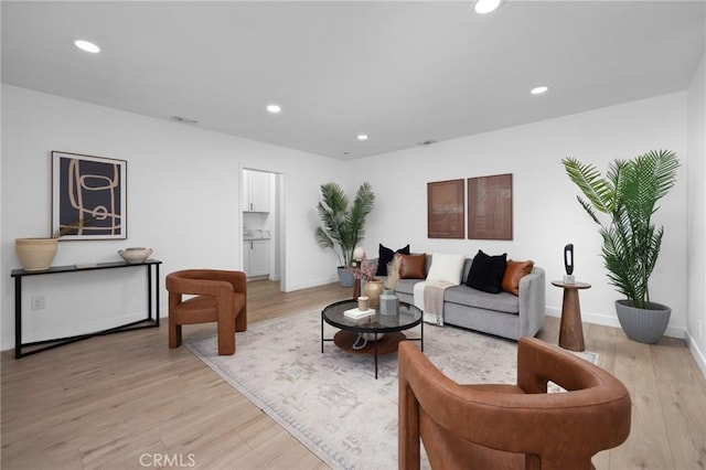 living room featuring light wood-style flooring, baseboards, and recessed lighting