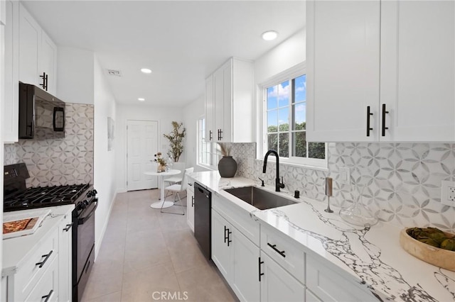 kitchen with light stone counters, visible vents, white cabinetry, a sink, and black appliances