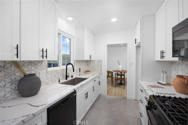 kitchen with black appliances, a sink, white cabinetry, and light stone countertops