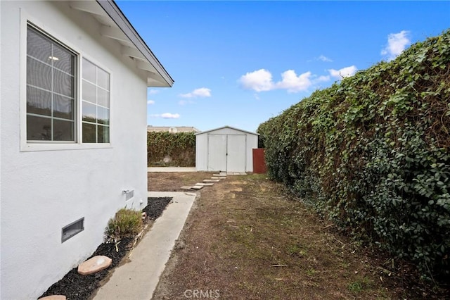 view of yard featuring an outbuilding, fence, and a shed