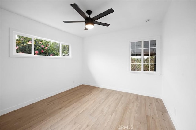 empty room featuring baseboards, a ceiling fan, and light wood-style floors