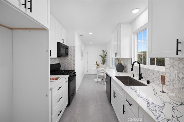 kitchen featuring black appliances, a sink, light stone countertops, and white cabinets