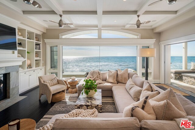 living room with a premium fireplace, a water view, a healthy amount of sunlight, and ceiling fan