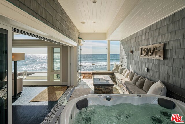 interior space featuring a hot tub, wooden ceiling, a healthy amount of sunlight, and a water view