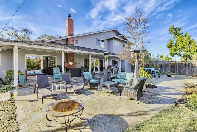 rear view of house with a patio and an outdoor living space with a fire pit