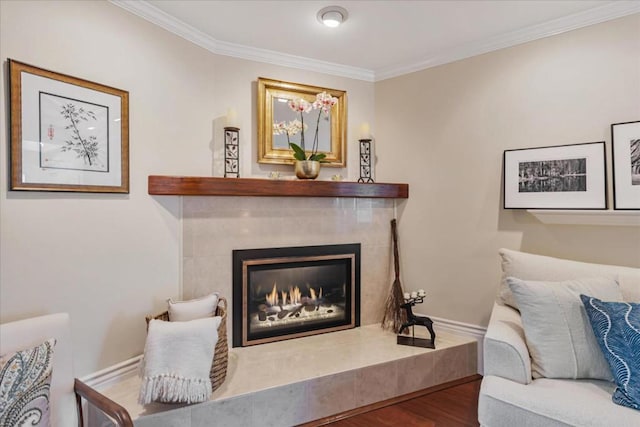 living area with crown molding, wood-type flooring, and a tile fireplace