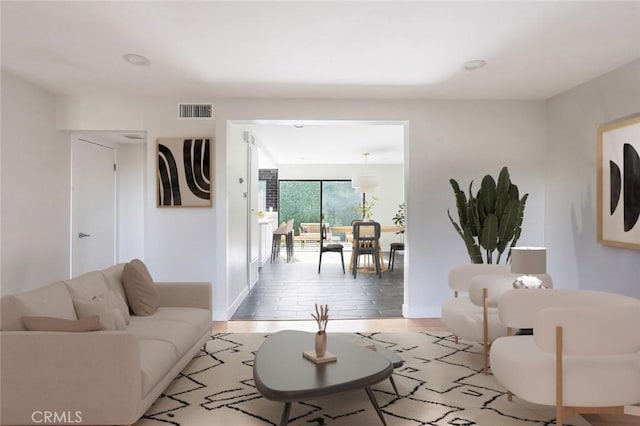 living room with baseboards, visible vents, and light wood finished floors