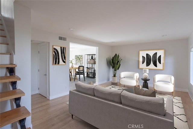 living room featuring light wood finished floors, baseboards, visible vents, stairway, and recessed lighting