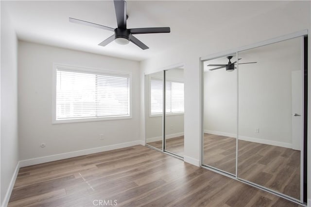 unfurnished bedroom with baseboards, multiple closets, and wood finished floors