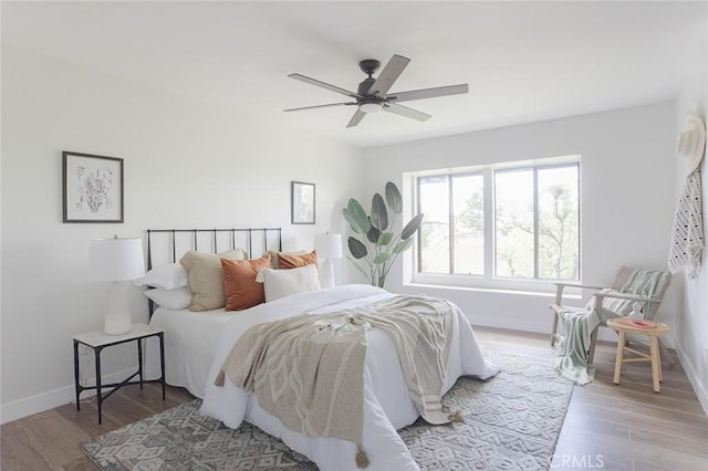 bedroom with a ceiling fan, baseboards, and light wood-style floors