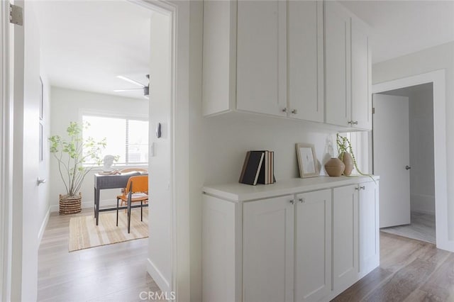 hall with baseboards and light wood finished floors