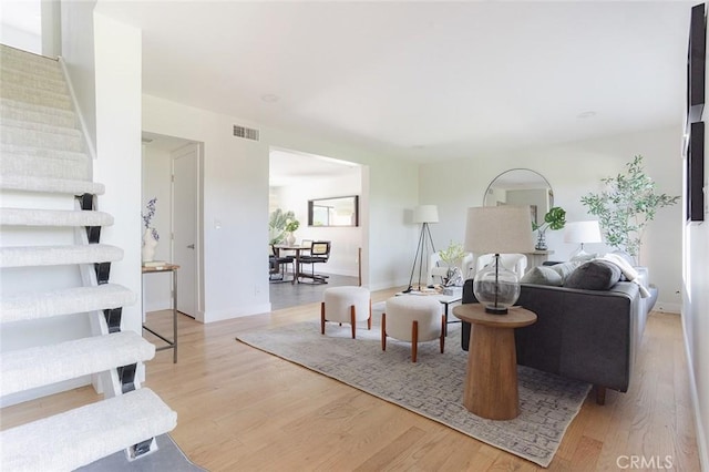 living area featuring visible vents, baseboards, and wood finished floors