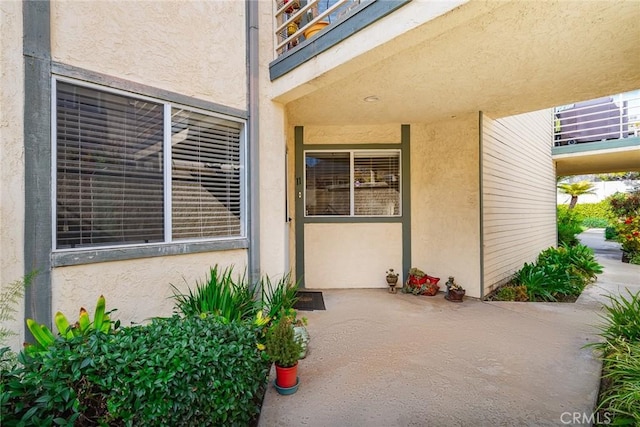 view of exterior entry featuring a balcony and a patio area