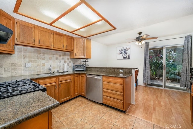 kitchen featuring tasteful backsplash, dishwasher, sink, exhaust hood, and kitchen peninsula