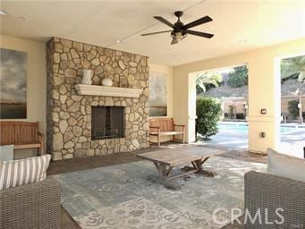 living room with a stone fireplace, plenty of natural light, and ceiling fan