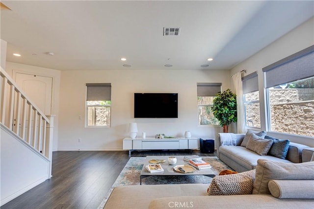 living room with dark hardwood / wood-style floors and a healthy amount of sunlight