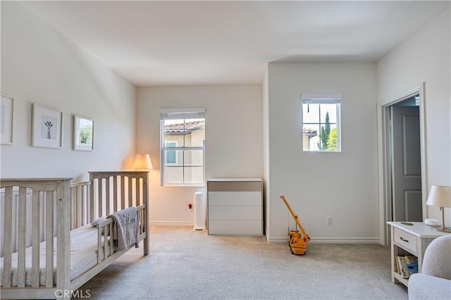 bedroom with light colored carpet, multiple windows, and a crib