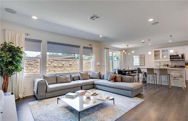 living room with an inviting chandelier and dark wood-type flooring