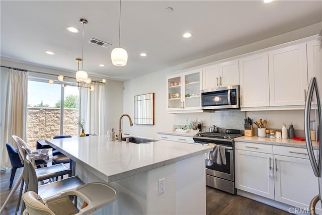 kitchen featuring appliances with stainless steel finishes, pendant lighting, sink, white cabinets, and light stone countertops