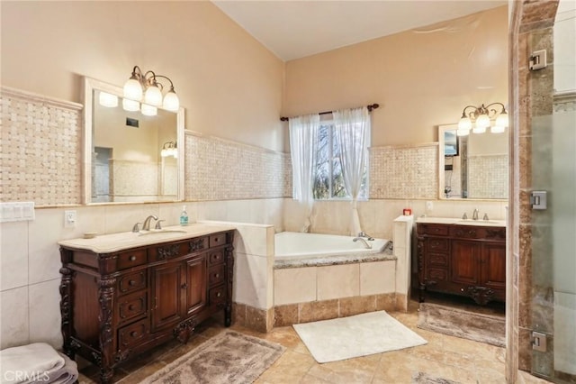 bathroom with vanity, tiled bath, tile patterned flooring, and tile walls