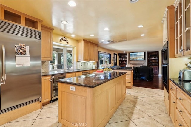 kitchen featuring a kitchen island, stainless steel built in refrigerator, beverage cooler, light tile patterned floors, and light brown cabinets