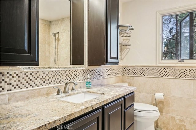 bathroom with walk in shower, vanity, toilet, and tile walls