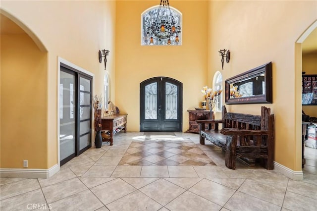 tiled foyer entrance featuring a towering ceiling and french doors