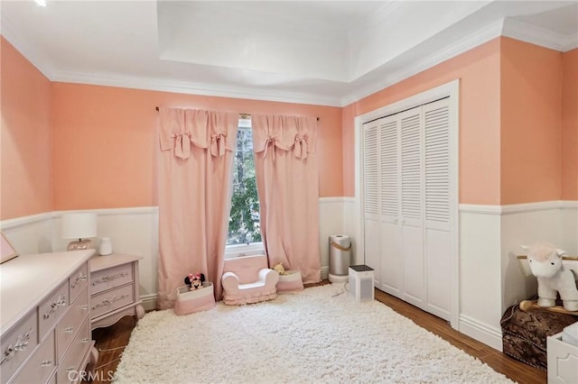 bedroom featuring ornamental molding, dark hardwood / wood-style flooring, a raised ceiling, and a closet