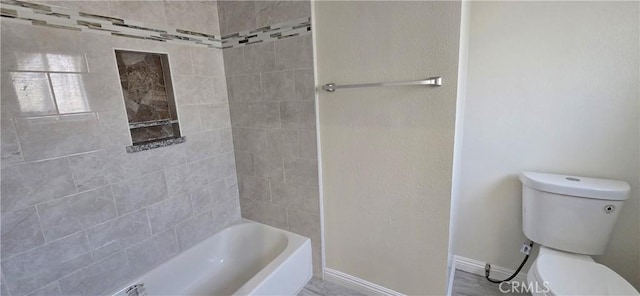 bathroom featuring tiled shower / bath combo and toilet